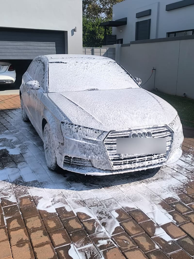 Silver Audi A3 covered in snow foam on a residential driveway during a mobile wash and wax