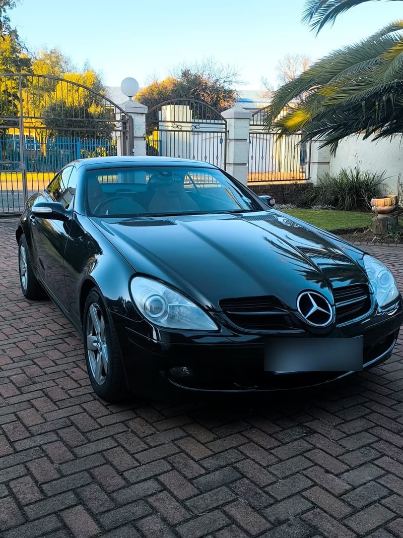 Mercedes-Benz SLK in gloss black after a full detail, photographed on a driveway at golden hour